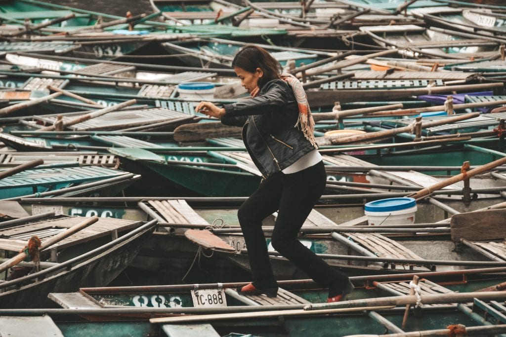 Vrouw loopt over de bootje in de haven van Tam Coc.