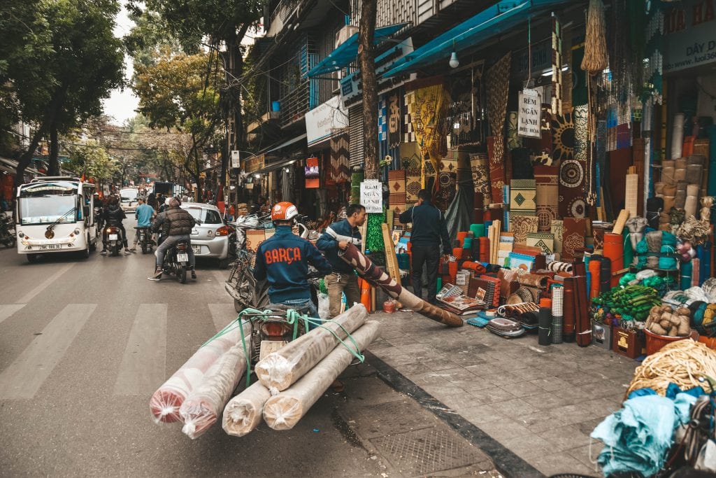 Overbepakte scooter met vloerkleden in Hanoi.